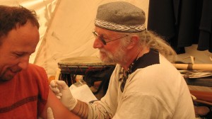 Erik Reime tatoverer et vognhjul på den gammeldags facon i Sagnlandet Lejre. Foto: Louise Lamberth, Tektsfokus.